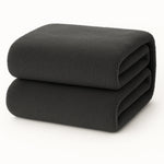 Een netjes opgevouwen Teddy fleece hoeslaken in donkergrijs, extra warm, afmeting 90x200 cm, op een witte achtergrond.