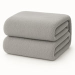 Een netjes opgevouwen Teddy fleece hoeslaken - 90x200 cm, lichtgrijs en extra warm, op een effen witte ondergrond.