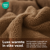 A close-up of soft, mink teddy fleece fabric with a fluffy texture. Dutch text highlights the luxurious warmth of the Teddy fleece hoeslaken - mink and mentions its OEKO-TEX certification.